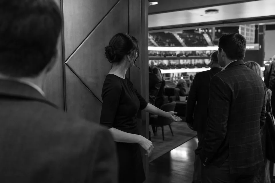 Hostessa wita gości w strefie partnera przed meczem koszykówki w hali sportowej