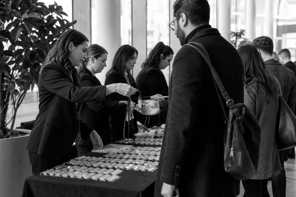 Hostessy wydają identyfikatory uczestnikom przy stanowiskach rejestracji w foyer centrum konferencyjnego